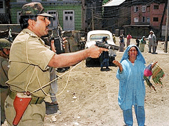 An indian para military official weilds a pistol as he orders a Kashmiri woman to go no further after a rocket attack on 19 May 2000. Three civilians including a child were wounded when a rocket fired by unidentified militants exploded near a residential house of Maisuma in the heart of Srinagar, the summer capital of Jammu and Kashmir