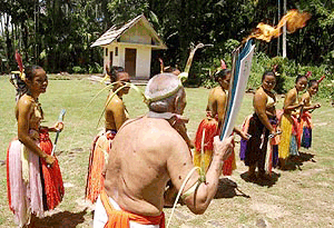 Torchbearer Chief Rurcherudel Lyechad, is welcomed by a dance troupe in traditional costumes, as he carries the Olympic Flame through the Pacific island of Palau, on Tuesday