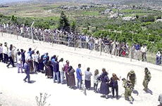 Israeli Arabs talk to their relatives from Lebanon on the Israel Lebanon border near the village of Arab El Aramsh on Sunday. Hundreds of Lebanese, guerrillas and civilians, have been converging on the border fence since Israeli troops hastily withdrew on Wednesday from Lebanon after an 18-year occupation.