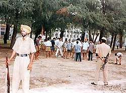 Punjab Police personnel stand guard as RSS activists perform their morning drill in Kidwai Park, Ludhiana, on Monday