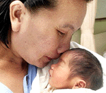 Boonying Khanthachana, 31, kisses her three-day old baby boy during a press conference at Chulalongkon hospital in Bangkok on Thursday. The baby, Thai obstetricians claimed they have brought to the world a baby boy conceived in the tubal-ligated mother's abdominal