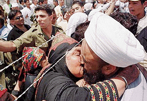 A Palestinian woman, who came from the Israeli side of the Lebanese-Israeli border, kisses a Muslim cleric who is a relative, at the Lebanese village of Dohaira on Saturday. Since Israel withdrew its troops from southern Lebanon Last week, hundreds of Palestinians have been gathering at Dohaira almost every day to meet with relatives and friends in Israel across the barbed wire fence on the border. There are 350,000 Palestinians living in 12 refugee camps across Lebanon