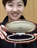 An employee of K.Mikimoto and Co. Ltd. shows off a pearl necklace given to US actress Marilyn Monroe by American baseball player Joe DiMaggio during their 1954 honeymoon. The copy of the  necklace, priced at 1 million yen (US $ 9,300) is currently on sale. � AFP photo