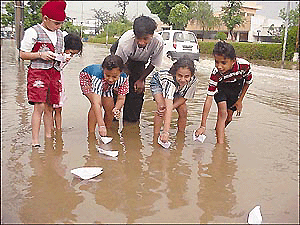 Children frolicking in rain and floating paper boats