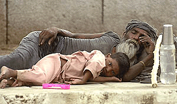 A street urchin is caught taking a nap next to a vagrant outside one of Delhi's many temples 14 June 2000.  Thousands of beggars and vagrants seeking a better life crowd the streets, temples and shanties of Delhi. The capital is home to some 10 million people. 