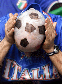 An Italian team supporter shows his head painted as a soccer ball
