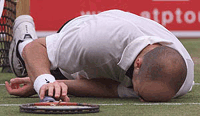Andre Agassi lies on the grass after slipping over during his third round tennis match against Italian Gianluca Pozzi on Thursday