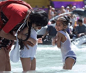 A woman and two children cool off in one of the fountains in Trafalgar Square in London on Sunday, as temperatures touch 30� centrigrade in the city