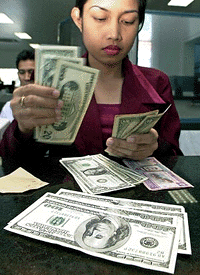 A teller exchanges US dollars for rupiah notes for a customer at a money changer in Jakarta on Wednesday