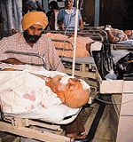Piara Singh lying in an unconscious state in the hospital as his nephew looks on 