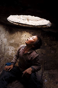 PEK55D:MONGOLIA:ULAN BATOR,12JUL00 - A Ulan Bator streetkid looks at the outside world through a manhole from his underground shelter July 4. Children from impoverished families hit hard by economic reforms since the fall of communism ten years ago are running away from home and spilling onto the streets. Estimates put the number of streetkids living at the capital city's underground sewage system as high as 10,000. The Mongolian Government has yet to come up with any plan to rescue its underprivileged children. Picture taken July 4.  asw/Photo by Andrew Wong REUTERS