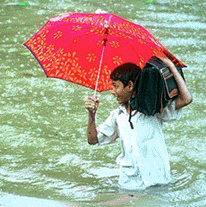 A schoolboy wades through a rain-flooded street