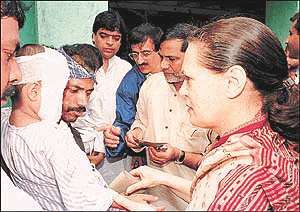 Congress President Sonia Gandhi gives a cheque for Rs 25,000 to a five-year-old boy who was injured in a recent monsoon landslide in Mumbai on Saturday. As rains subsided on Saturday, Mumbai was left racked with grief and shame after a landslide killed at least 69 of its poorest citizens earlier this week. The toll is expected to rise