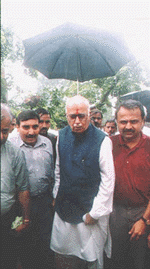 Union Home Minister L.K. Advani under the shelter of umbrella visiting the rain-hit Ahmedabad city on Saturday