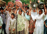 Women  protesters from a Karachi slum holding empty jars and pans.
