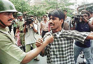A policeman (L) catches a youth by his shirt after he along with other Congress Party supporters set a bus ablaze during a general strike called by the Congress Party on Monday  in Calcutta to protest against the massacre of eleven people last week allegedly by Communist Party workers in the Birbhum district, in the eastern Indian state of West Bengal. The protesters threw stones and broke the windows of several privately owned vehicles
