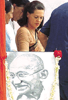 Sonia Gandhi, leader of the  Congress, walks past a photograph of Mahatma Gandhi, after addressing a rally in New Delhi on Wednesday.