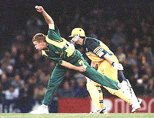 South African captain Shaun Pollock bowls as his Australian counterpart Steve Waugh looks on during their first one day cricket match in Melbourne, on Wendesday
