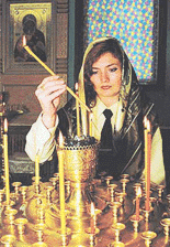 A member of the military staff lights a candle for the sailors aboard the Kursk submarine during an Orthodox service at the Severomorsk naval base in northern Russia on Friday