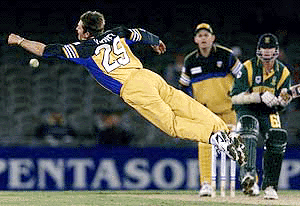 Australia's Ian Harvey (L) dives to stop a ball hit by South Africa's Lance Klusener (R) as wicket-keeper Adam Gilchrist looks on during the second one-day match in the Super Challenge 2000 series at Melbourne's Docklands Stadium on Friday