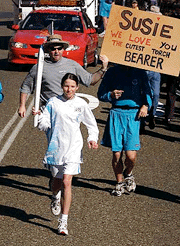 Susan Wilton carries the flame with some support from her family and friends displaying a poster "Susie, We love you, The Cutest Torchbearer" at Warialda, New South Wales August on Monday