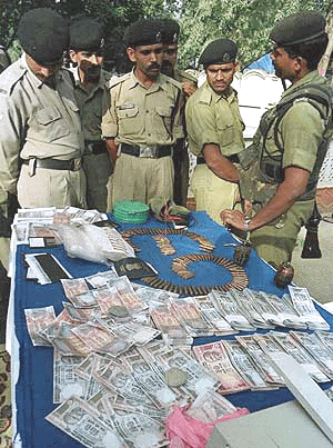 An Indian paramilitary trooper shows fake currency and ammunition at a paramilitary camp in Srinagar on Monday. A paramilitary official said they recovered at least 4 million rupee of a total of at least 5.7 million counterfeit currency that had been circulated in Kashmir