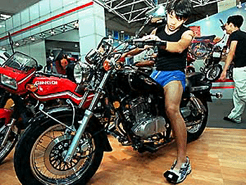 A young man tries out a new foreign type of motorbike produced by a Chinese factory, at a motorbike trade show in Shanghai in Wednesday. Foreign companies are planning to increase their China investments after China's expected entry into the WTO � AFP photo