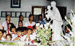 A group of children sign hymns in front of the Tomb of Mother Teresa at Mother House on the occasion of her 90th birth anniversary in Calcutta on Saturday