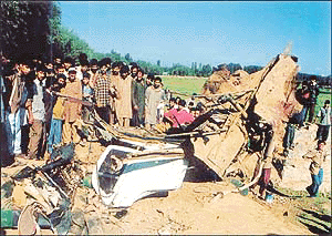 Residents gather around the debris of the car which was blown up in a landmine blast in which a former Minister, Maulavi Iftikhar Ansari, was injured at Pattan in Baramullah district
