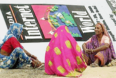 Women workers take a break on Tuesday in front of a banner during preparations for �India Internet World Show 2000� beginning on Wednesday. 