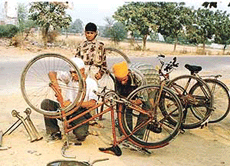 Charanjit Singh (right), a riot victim, repairs a bicycle in Ludhiana. 