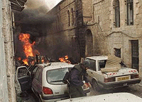 An explosives expert checks vehicles close to site where a car-bomb exploded (rear) near the Mahane Yehuda market in the heart of Jerusalem on Thursday evening killing two people.