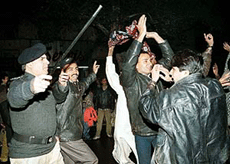 A police officer (left) tries to stop residents from celebrating the new year on Sunday night in Lahore.