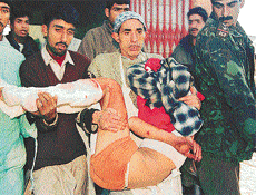 An injured Kashmiri is rushed to hospital for treatment as a policeman looks on after a grenade explosion at Sopore, 48 km northwest of Srinagar.