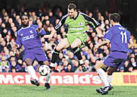 Peterborough United's David Farrel (center) charges past Chelsea's captain Dennis Wise (right) and Nigerian midfielder Celestine Babayaro