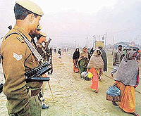 Armed policemen watch devotees make their way to compounds near the Ganga in Allahabad on Monday to take part in the Kumbh Mela.