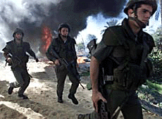 Israeli soldiers run past a large fire burning in the Gush Katif settlement bloc in the Gaza Strip on Monday.