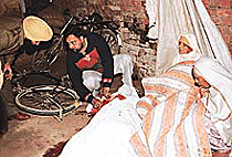 Swaroop Singh lies in a pool of blood on the ground as his son Jasbir Jassi shows the wounds to a policeman in Nabha village near Zirakpur.