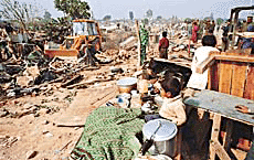 A child looks on as the JCB of HUDA razes his house to the ground in Rajiv Colony