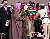 Former US President George Bush watches as the Emir of Kuwait, Sheikh Jaber al-Ahmad al-Sabah, kisses a Kuwaiti flag before a flag raising ceremony in Kuwait on Sunday.
