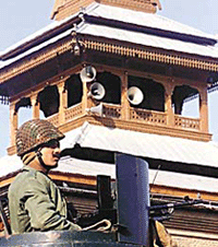 A paramilitary jawan stands guard atop his armoured vehicle near a minaret of Srinagar�s grand mosque on Thursday. 