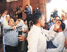 Security personnel try to pacify BJP and Opposition MPs shouting slogans against each other at the Parliament complex in New Delhi on Thursday.
