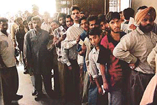 People standing in long queues for depositing their telephone bills. 