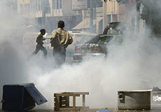 Protesters run for shelter amidst tear gas in Karachi on Monday.