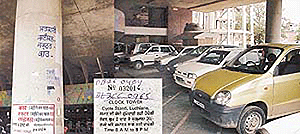 The details of parking fee covered with paint at the entrance of the parking lot at the old headquarters of the Municipal Corporation on Mata Rani Road, Ludhiana, and (inset) a parking-fee receipt bearing two registration numbers.