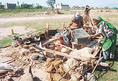 Jhuggi-dwellers pick up their belongings after the police removed their jhuggis in Sector 12, Panchkula, on Sunday.