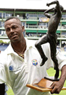 West Indies fast bowler Courtney Walsh holds a statue of himself as he was honoured by the West Indies Cricket Board at the Sabina Park in Kingston, Jamaica on Saturday. 