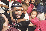 Hasim ��The Rock�� Rahman carries his cousin Marcquis Wilson (6) on his shoulder as he makes his way through a throng of wellwishers inside a sporting store in downtown Baltimore on Monday as he returned from South Africa where he knocked out Lennox Lewis to take two heavyweight titles.