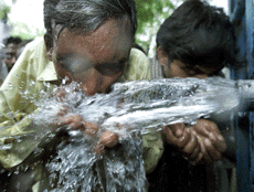 An Indian man drinks water from a metal pipe attached to a tank on a street in New Delhi, May 1, 2001. 