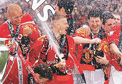 Manchester United players celebrate with champagne and the English Premier league trophy, following the match against Derby County at Old Trafford Stadium in Manchester on Saturday. 